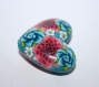 Une perle forme coeur en polymère, motif fleuri bleu rose