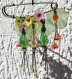 Dèlicate broche en bronze avec des petites fleurs multicolores, ainsi que des perles et des gouttes en verre