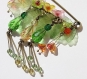 Dèlicate broche en bronze avec des petites fleurs multicolores, ainsi que des perles et des gouttes en verre
