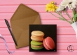 Carte postale « macarons » illustrée de 3 macarons beige, rose et vert sur fond noir